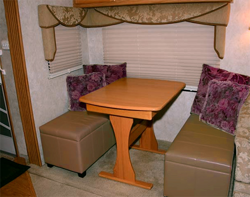 Dining area inside a Fifth Wheel with an Ottoman added for seating